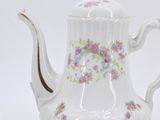 a white tea pot with a floral design on it