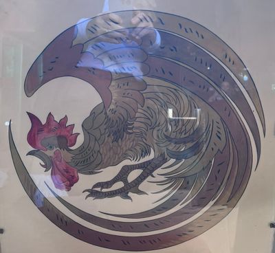 a picture of a rooster on display in a glass case