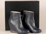 une paire de bottines à talons compensés en cuir bleu, dans une boîte noire
