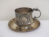 a silver cup and saucer sitting on a white table