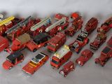 a lot of toy firetrucks and trucks on a white surface