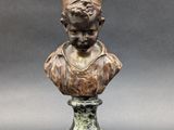 a bronze bust of a man with a hat on top of a marble base