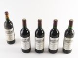 six bottles of wine are lined up in a row on a white surface