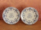 deux assiettes bleues et blanches ornées d'un monogramme, posées sur une table
