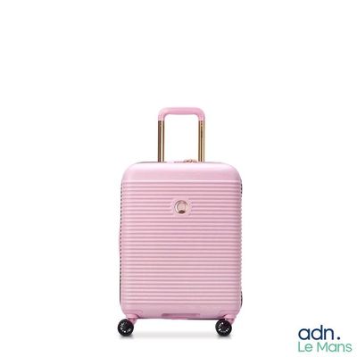 La valise rose repose sur ses roulettes, posée sur une surface blanche.
