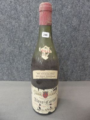 Des bouteilles de vin sont posées sur une table devant un mur gris.