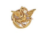a close up of a gold brooch with a bird on it