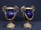pair of blue vases with gold accents on stands against a black background