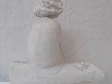 a statue of a woman sitting on a boat made out of clay