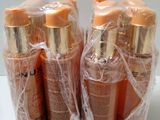 three bottles of tanning lotion wrapped in plastic on a white surface