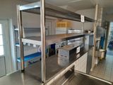a man standing in a kitchen next to a stainless steel shelf