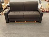 the couch is in a warehouse with boxes and pallets in the background
