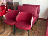 three red chairs in a room with a chalkboard on the wall