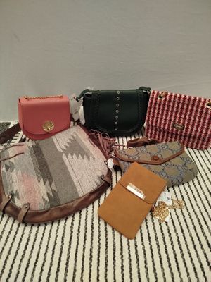 bags and wallets laid out on a bed with a striped blanket