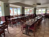 Ce restaurant, qui dispose de nombreuses fenêtres, compte de nombreuses tables et chaises.