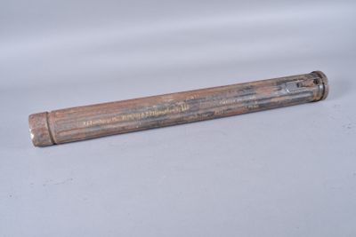 un tube en bois portant une inscription, posé sur une surface blanche