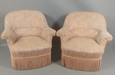 pair of upholstered chairs with fringed arms and foot rest