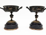 pair of black and gold vases on pedestals on a white background