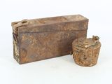 une vieille boîte rouillée et une tasse posées sur une surface blanche