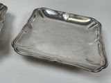 two silver trays sitting on a white table