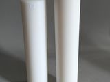 deux vases blancs posés l'un à côté de l'autre sur une table