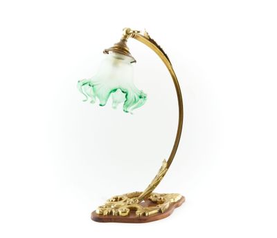 une image représentant une lampe avec un abat-jour en verre vert posé sur un socle en bois