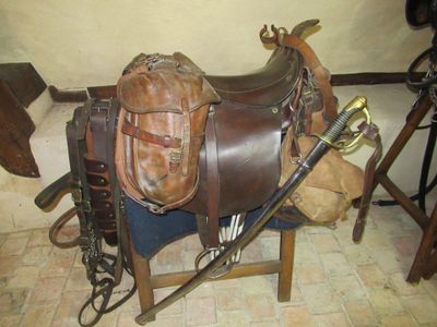 a saddle and a pair of boots on a chair