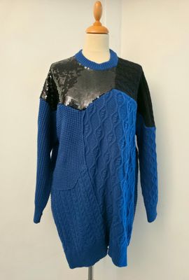 Le pull est bleu et noir, avec des paillettes.