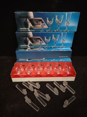 trois cartons de verres à vin et un service de couteaux posés sur une table
