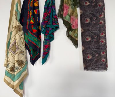 several different colored scarves hanging on a white wall in a room