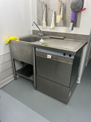 a kitchen with a sink, dishwasher, and other items hanging on the wall