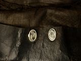 a pair of silver earrings sitting on top of a piece of wood