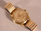 a gold wrist watch on a white surface