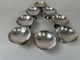 six silverplated dishes arranged in a triangle on a table