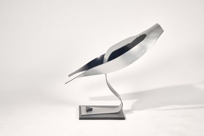 une sculpture métallique représentant un oiseau, posée sur un socle