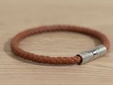 leather bracelet with a silver clasp on a wooden surface