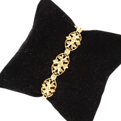 un gros plan d'un bracelet en or posé sur un coussin en velours noir