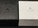 une boîte noire et blanche sur laquelle figure un logo argenté