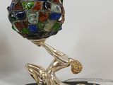 a sculpture of a person holding a ball on a stand