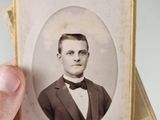 a man in a suit and bow tie holding a small picture