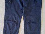 un pantalon cargo bleu marine posé sur un lit recouvert d'un drap blanc