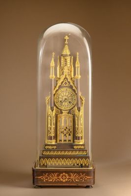 a gold clock under a glass dome on a table