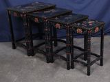 trois tables gigognes noires et rouges posées sur un sol en béton