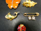 quatre broches et une épingle posées sur un fond noir
