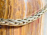 a close up of a gold chain on a wooden table