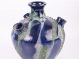 un vase bleu et vert posé sur une surface blanche