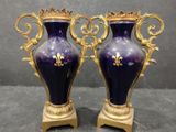pair of purple vases with gold accents on stands against a gray background