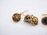three pieces of gold and black stone jewelry on a white surface