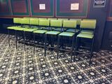 rows of green bar stools sit in front of a wall with pictures on it