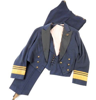 une veste bleu marine avec des garnitures dorées, une chemise blanche et un pantalon blanc